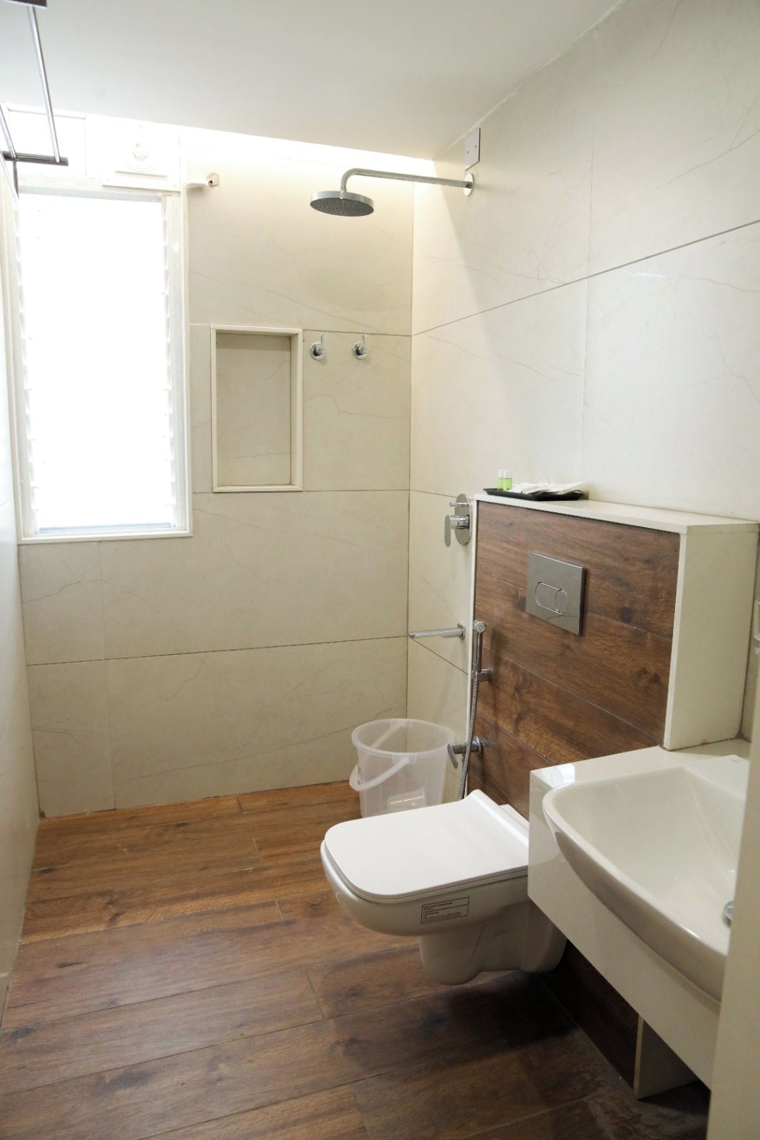 A bathroom with a wooden floor, a toilet, a sink, and a shower.