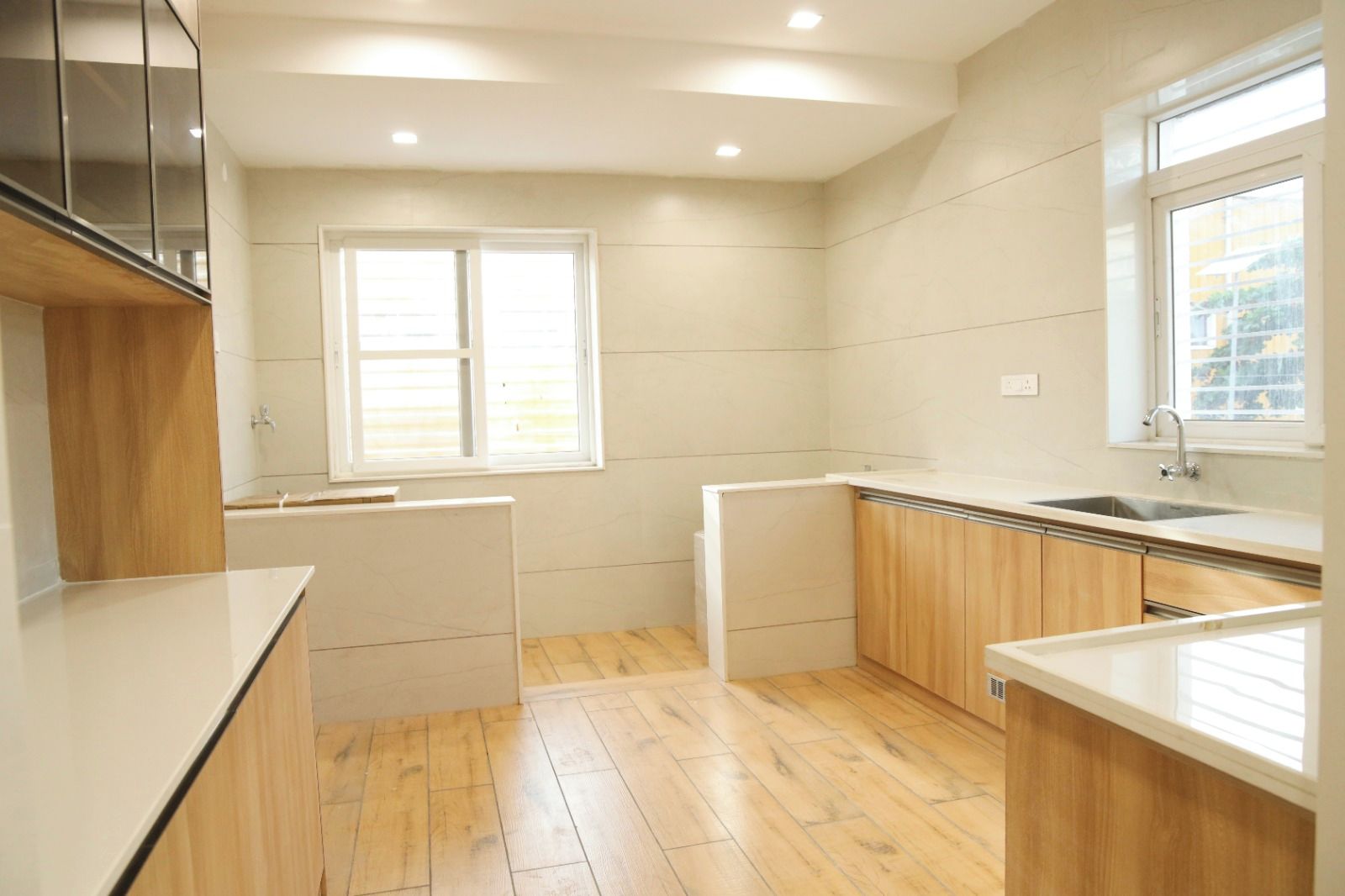 A modern kitchen with wooden cabinets, a white countertop, and a window providing natural light.