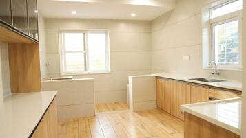 A modern kitchen with wooden cabinets, a white countertop, and a window providing natural light.
