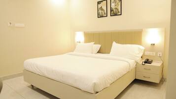 A hotel room with a bed, bedside tables, a telephone, and wall-mounted lights.