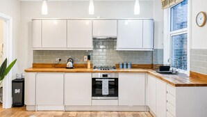 Une cuisine moderne avec des armoires blanches, un plan de travail en bois, un four encastré et une fenêtre offrant une belle vue.