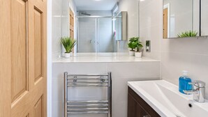 Une salle de bain moderne avec une douche à parois de verre, un lavabo blanc et un porte-serviettes.