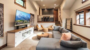 A spacious living room with a large sectional sofa, a flat-screen TV, and a wooden coffee table.