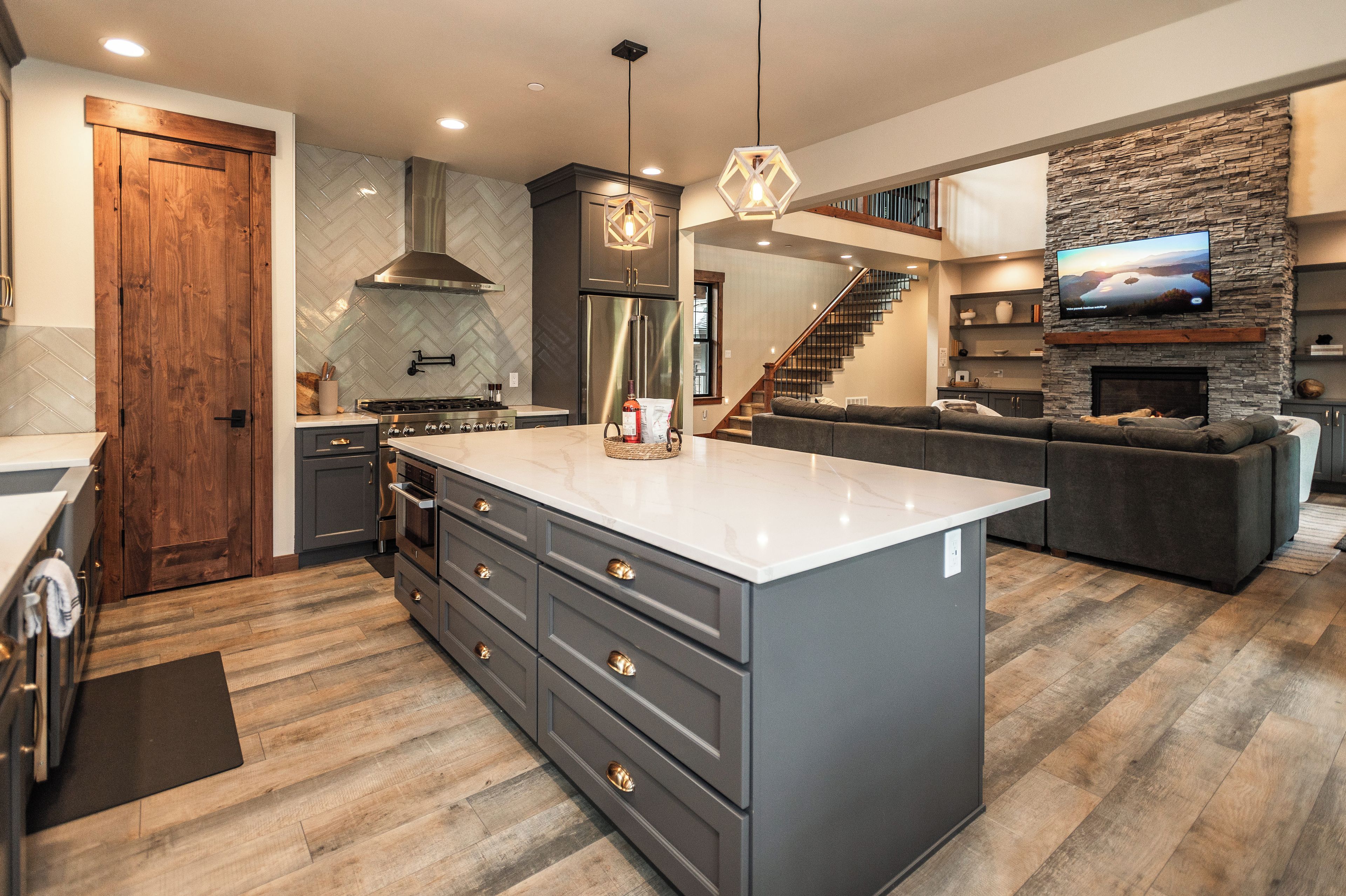 A modern kitchen with a large island, built-in appliances, and a stone accent wall.