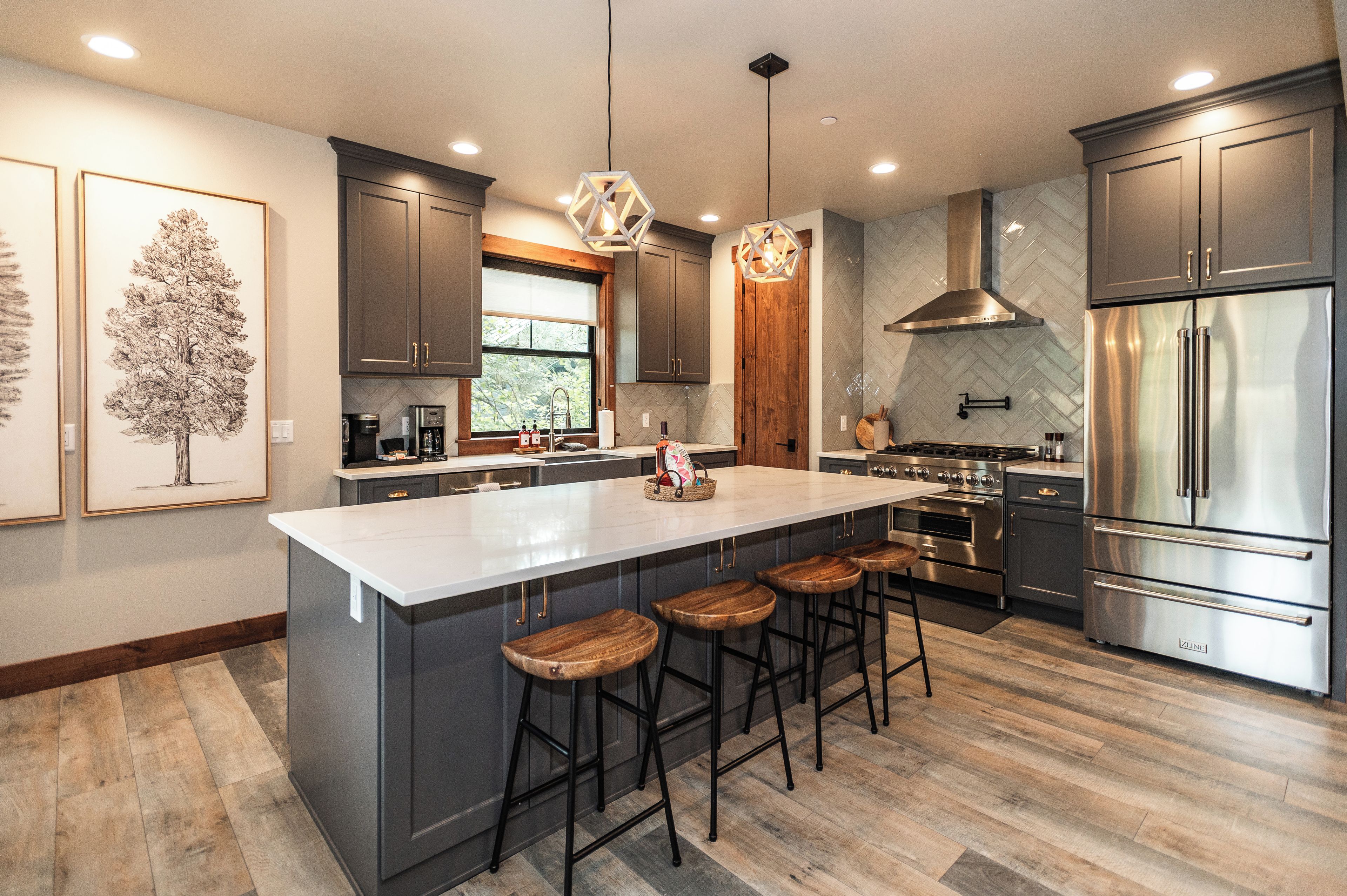 A modern kitchen with a large island, stainless steel appliances, and wooden bar stools.