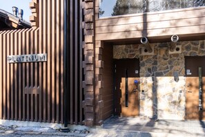A building entrance with a metal gate labeled 'PLATINUM,' stone walls, and a wooden door with a number 'B3' sign. - Hiihtäjänkuja 2 B4 by Holiday in Lapland (Levi)