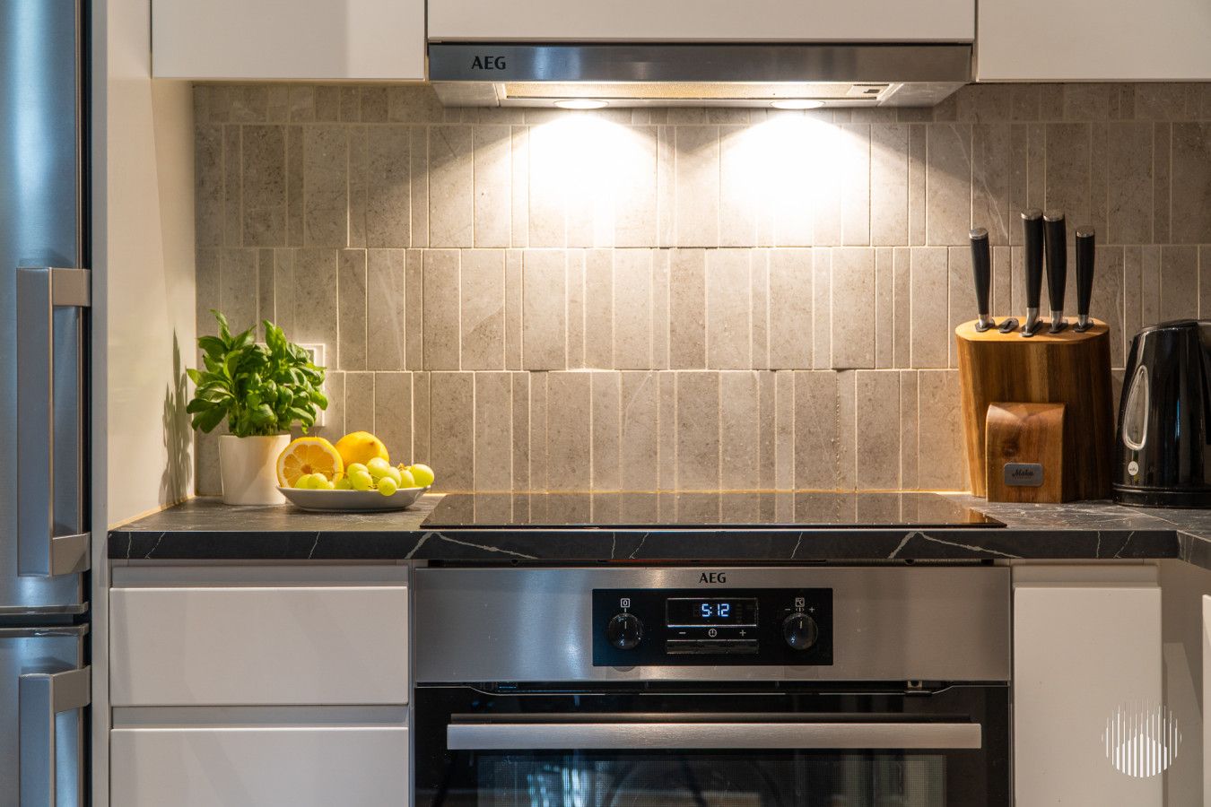 A kitchen with a stainless steel range hood, a digital clock, and a knife block.