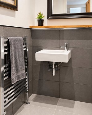Ein modernes Badezimmer mit integriertem Waschbecken, einem Handtuchhalter und einer Topfpflanze.