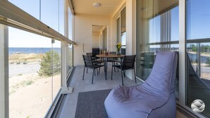 A balcony with a table and chairs, a cushioned seating area, and a view of the sea. - Keskuskarintie 120 by Holiday in Kalajoki (Kalajoki)