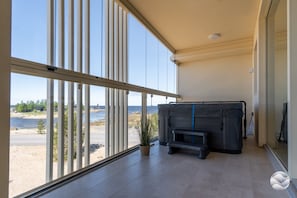 A balcony with a view of a beach and a large black object, possibly a piece of furniture.