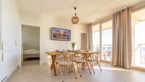 A spacious room with a dining table, chairs, a bed, and a large window with curtains. - Keskuskarintie 120 by Holiday in Kalajoki (Kalajoki)