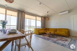 A modern living room with a yellow sofa, dining table, and chairs.