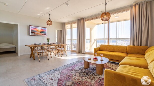A spacious living area with a yellow sofa, a round coffee table, and a dining table with chairs. - Keskuskarintie 120 by Holiday in Kalajoki (Kalajoki)