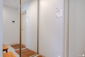 A hallway with a wooden floor, a glass door, and a wall-mounted fire safety sign.