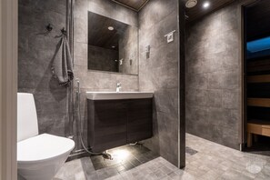 Ein modernes Badezimmer mit Toilette, Waschbecken und Duschbereich.