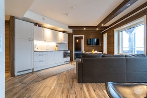 Eine moderne Küche mit weißen Schränken und einer Essecke mit einem grauen Sofa.