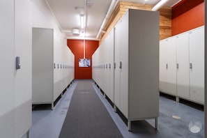 Ein Korridor mit Schließfächern, einer roten Wand und einer Decke mit Lüftungsöffnungen.