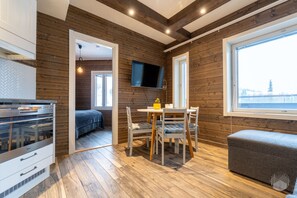 Ein Zimmer mit einem Bett, einem Esstisch mit Stühlen, einem an der Wand befestigten Fernseher und einem Fenster mit Blick.