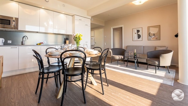 A modern kitchen with white cabinets, a dining area with a round table and chairs, and a living room with a sofa and coffee table. - Marinan Portin Majakka B13 by Holiday in Kalajoki (Kalajoki)