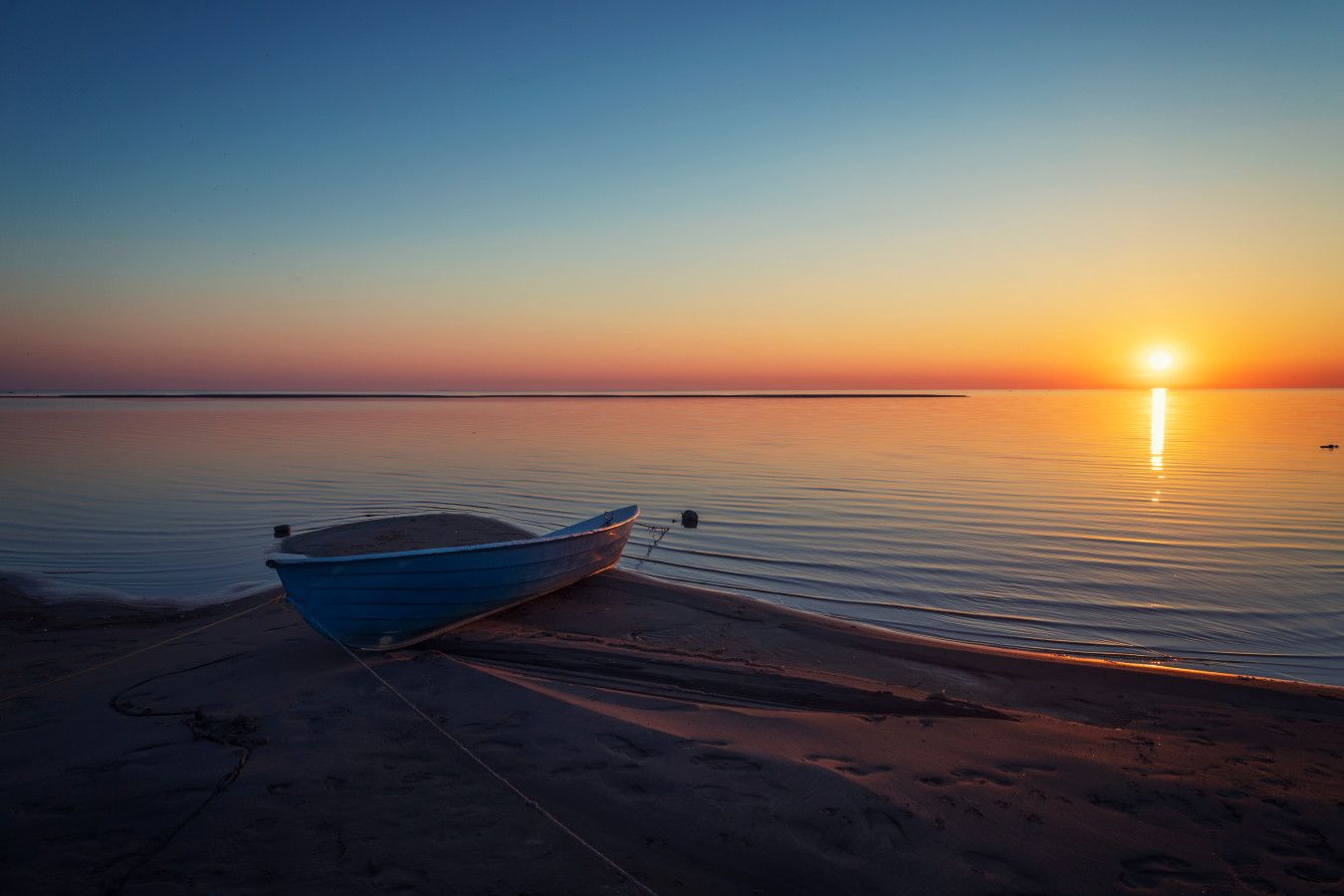 Een boot afgemeerd aan een steiger bij zonsondergang.