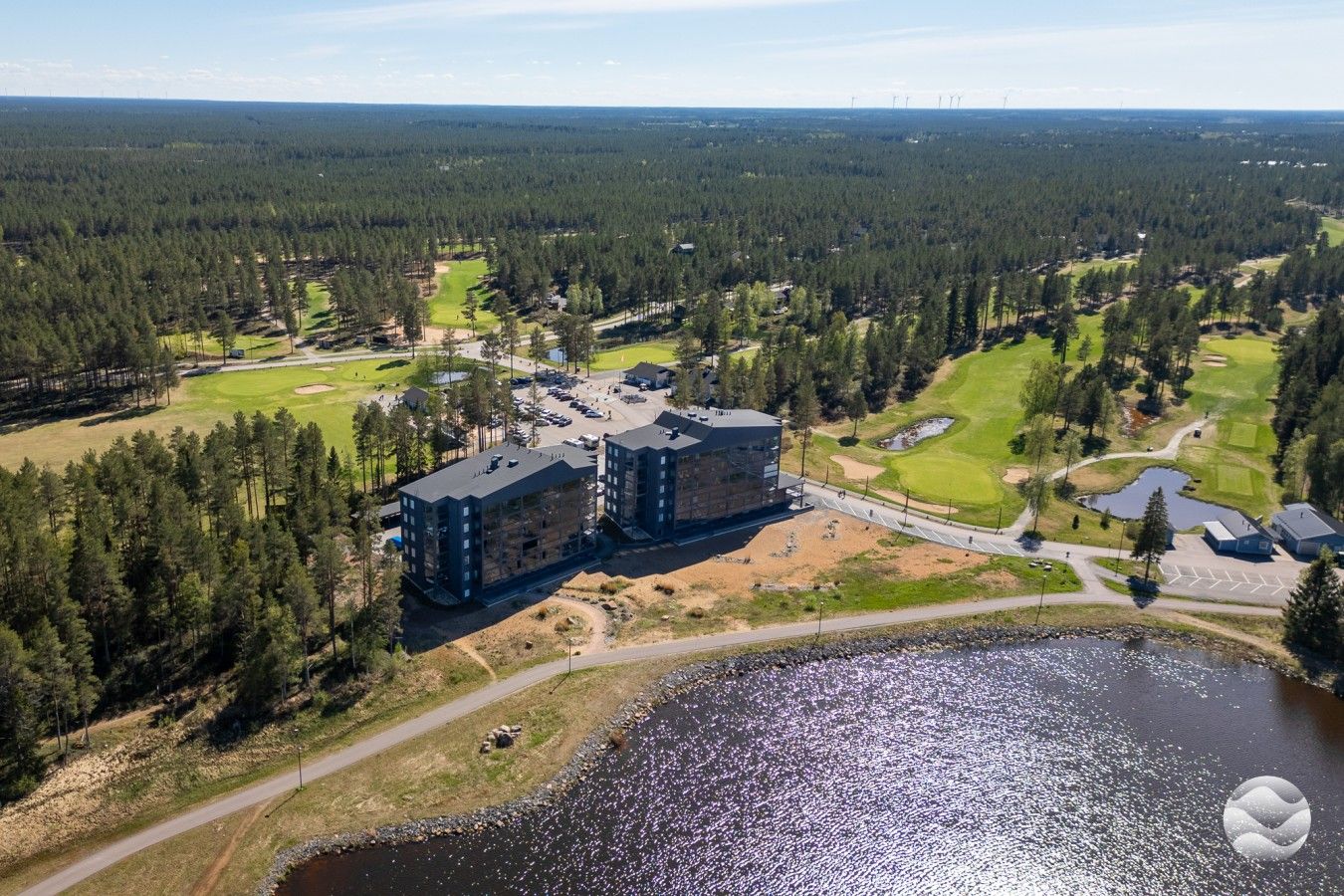 Un immeuble à plusieurs étages, avec un parking et un terrain de golf en arrière-plan.
