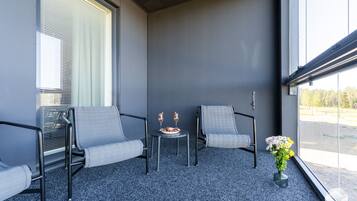 A balcony with two chairs, a small table, and a vase of flowers.