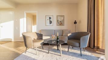 Ein modernes Wohnzimmer mit einer Couch, zwei Sesseln, einem Couchtisch und Kunstwerken an der Wand.