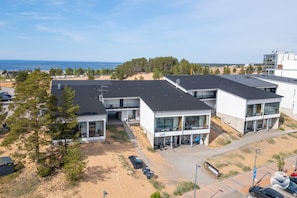 Ein modernes Gebäude mit mehreren Etagen, einem Parkplatz und Blick auf das Meer.