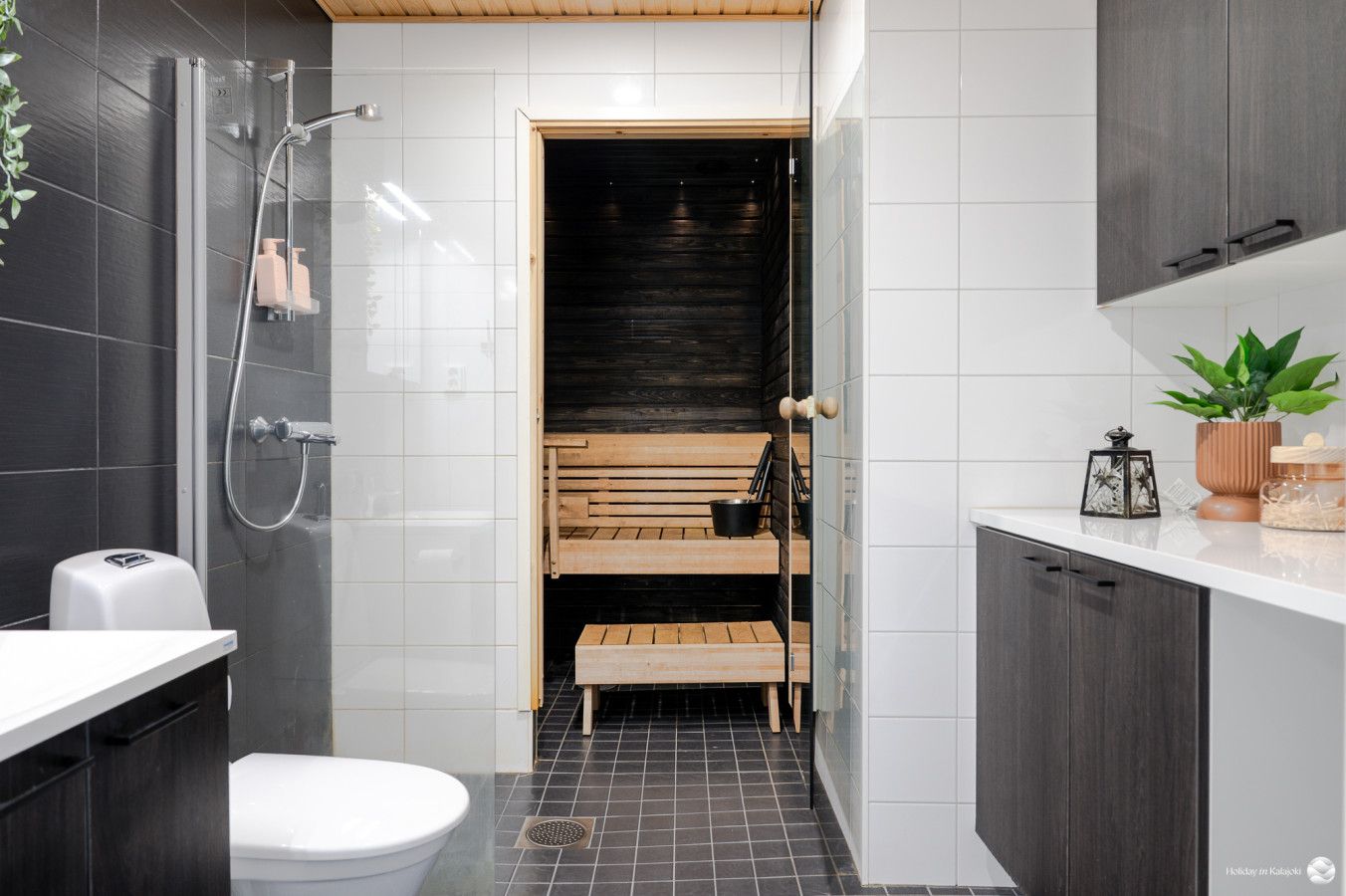 A modern bathroom with a shower, toilet, and a bench in the corner.