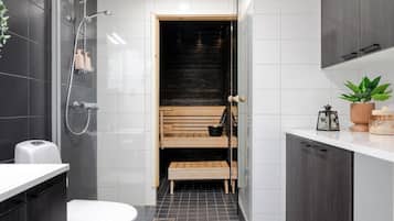 A modern bathroom with a shower, toilet, and a bench in the corner.