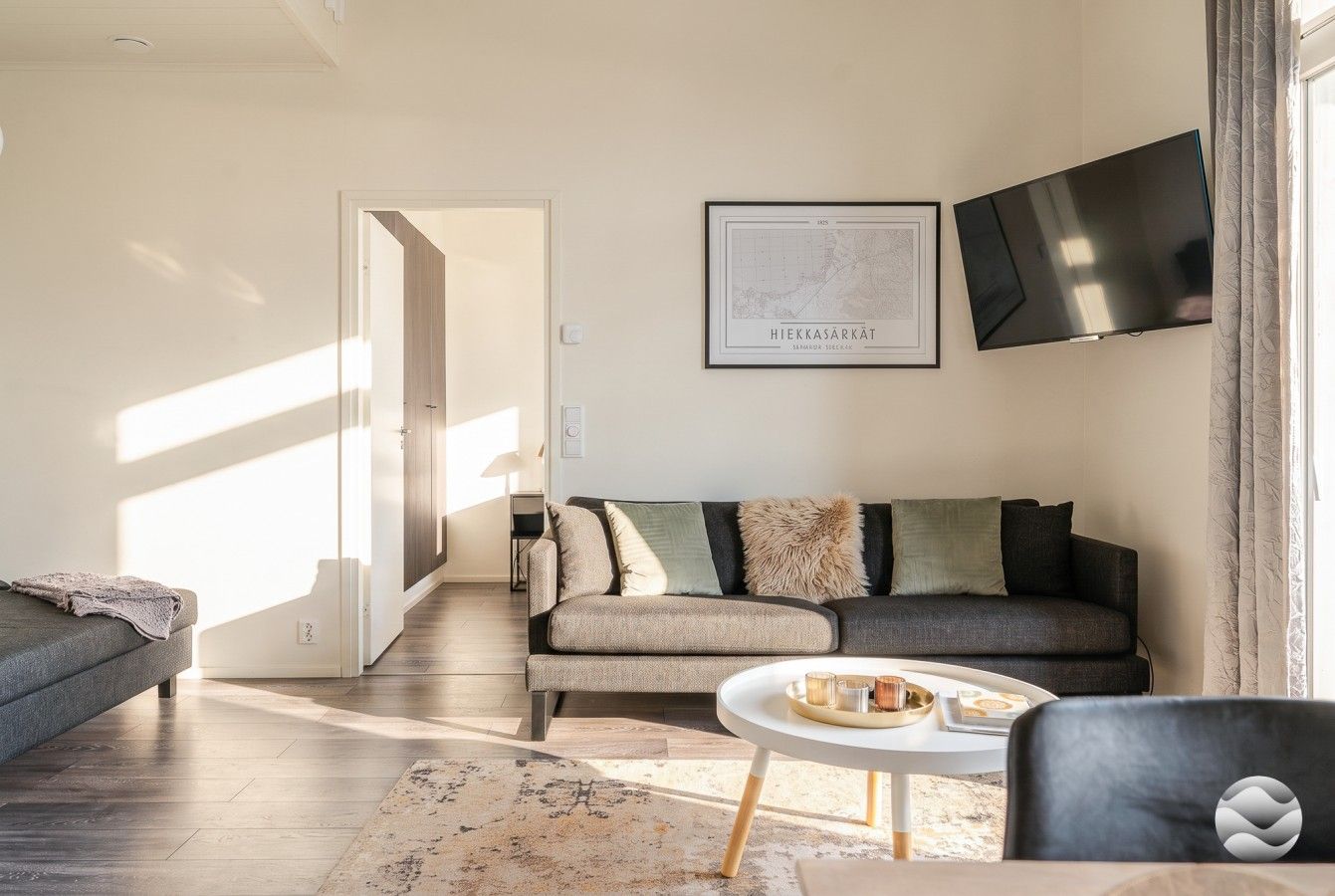 Una sala de estar moderna con un sofá, una mesa de centro y un televisor montado en la pared.