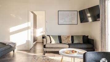 Una sala de estar moderna con un sofá, una mesa de centro y un televisor montado en la pared.