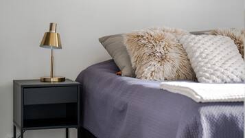 Een slaapkamer met een bed, een nachtkastje, een ingelijste kaart en een lamp.