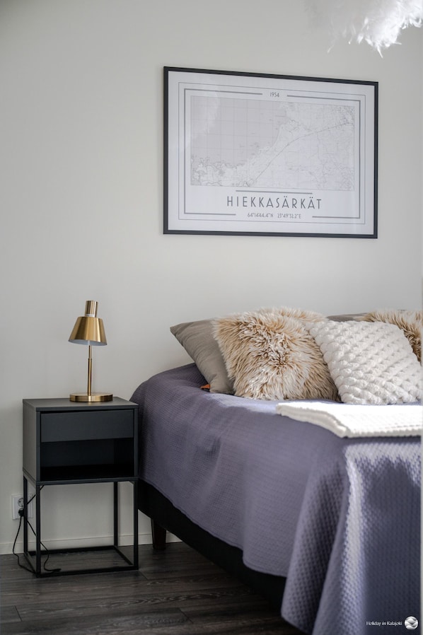 A bedroom with a bed, a nightstand, a framed map, and a lamp.