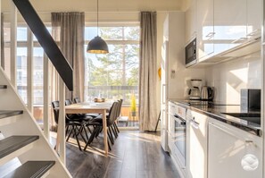 A modern kitchen with white cabinets, a dining area with a table and chairs, and a staircase leading to another level.
