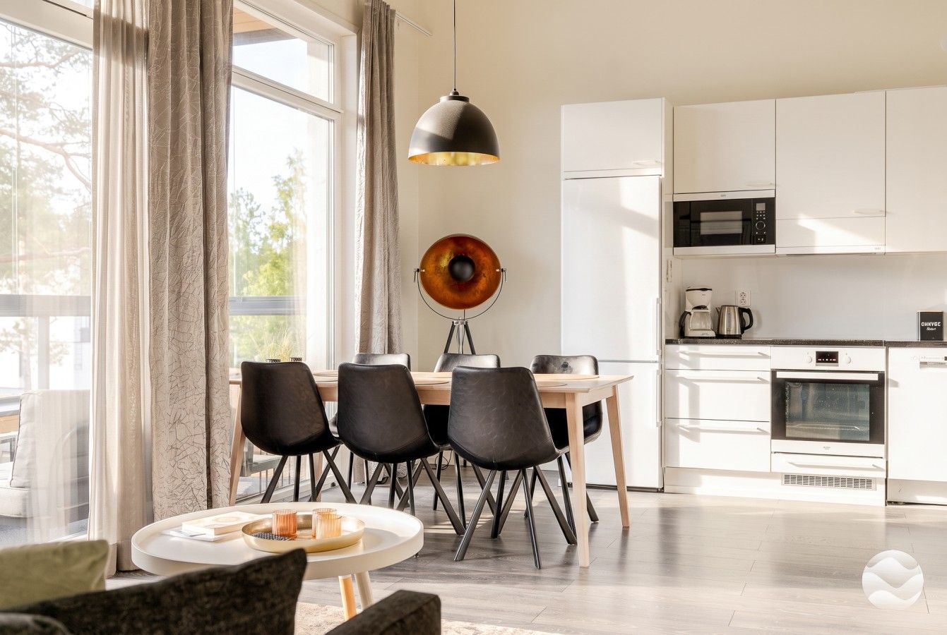 Een moderne keuken met witte kasten, een eettafel met stoelen en een hanglamp.