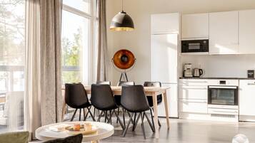Een moderne keuken met witte kasten, een eettafel met stoelen en een hanglamp.
