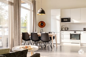 A modern kitchen with white cabinets, a dining table with chairs, and a pendant light.