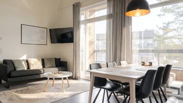 Uma sala de estar moderna com um sofá, uma mesa de centro redonda e uma área de jantar com mesa e cadeiras.