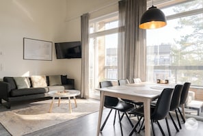 A modern living room with a sofa, a round coffee table, and a dining area with a table and chairs.