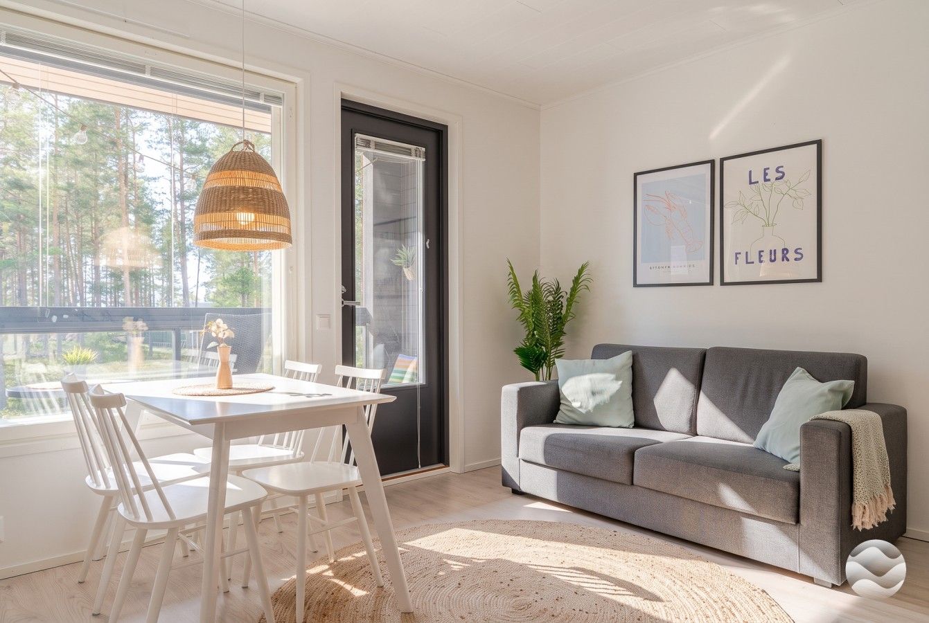 Una sala de estar moderna con una mesa de comedor, un sofá y un ventanal con vistas a árboles.