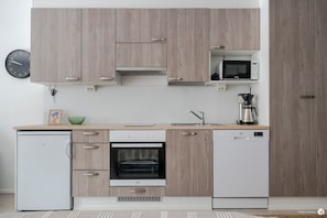 A modern kitchen with wooden cabinets, a built-in oven, a microwave, and a coffee maker.