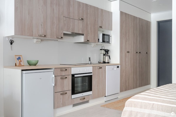 A modern kitchen with wooden cabinets, a microwave, a coffee maker, and a dishwasher.