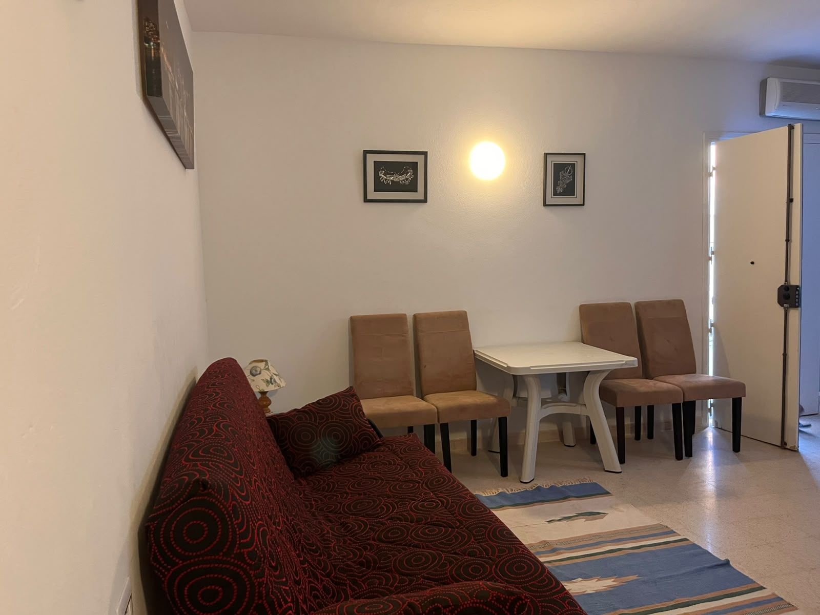 A living room with a sofa, a dining table with chairs, and a patterned rug.