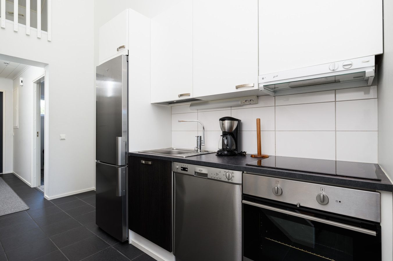 Una cocina moderna con electrodomésticos de acero inoxidable, lavavajillas y cafetera.