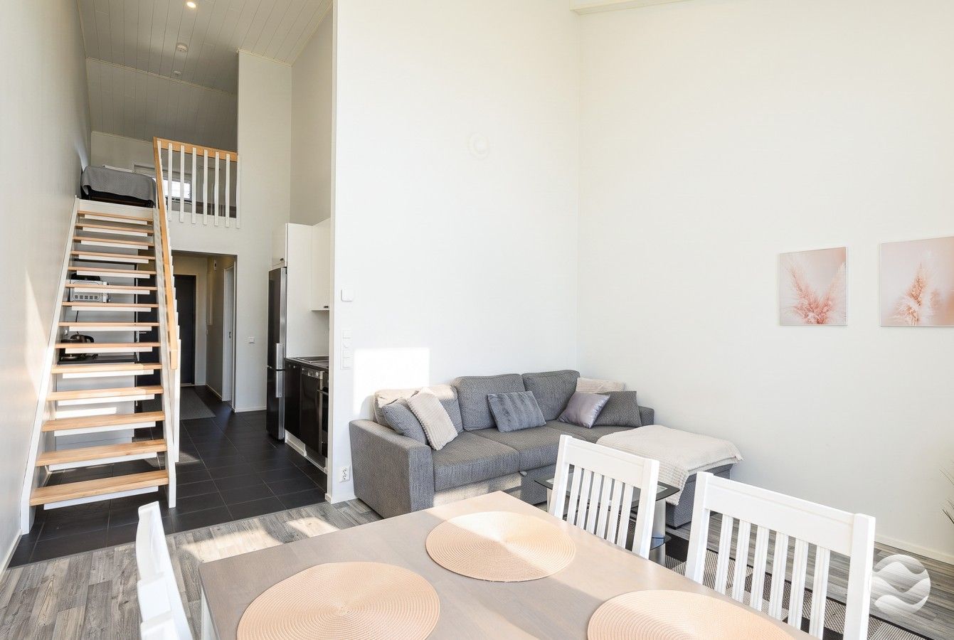 A modern interior with a dining area, a sofa set, and a staircase leading to an upper level.