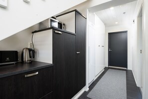 Une cuisine moderne avec des meubles de couleur sombre, une bouilloire et un four à micro-ondes.