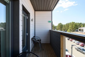 A balcony with a view of a parking lot and trees.