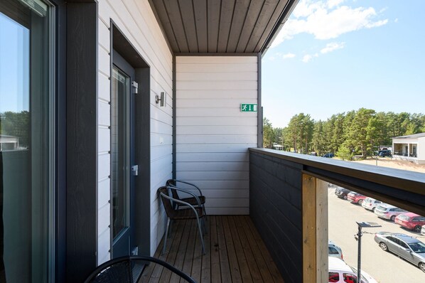 A balcony with a view of a parking lot and trees.