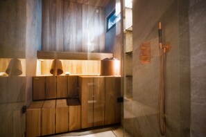 A sauna with wooden benches and a glass partition, a towel rack, and a shower area. - North Suite 11D by Holiday in Lapland (Levi)
